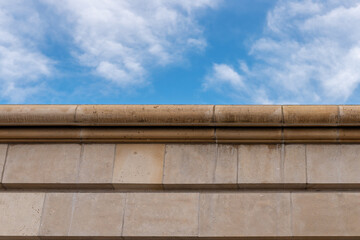 Stone wall made of dolomite against the blue sky. Rustication and cornice. Architectural detail