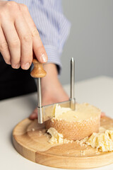 Round cheese knife. Tete de Moine. Woman cuts cheese. Girolle cheese knife. Soft focus