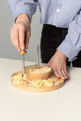 Round cheese knife. Tete de Moine. Woman cuts cheese. Girolle cheese knife. Slicing for serving