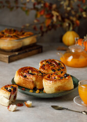 Naklejka na ściany i meble Buns with raisins and orange peel on grey background. Autumn buns with sea buckthorn tea. 