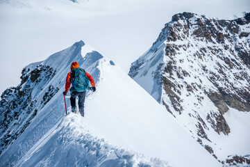 Fototapeta na wymiar Epic view on descending alpinist on a steep narrow snow ridge, extreme climbing mountaineer, Monch, Bernese Alps, Swiss