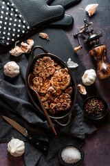 Roasted garlic fresh out of the oven with raw garlic bulbs and cloves all around