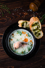 Traditional Finnish fish soup with salmon, cream, potatoes, dill and bread with sauce and spices.