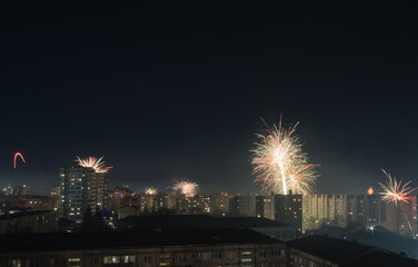 Fototapeta na wymiar Bright colorful and multi-colored fireworks on New Year's Eve over the city, fireworks explode over a residential city