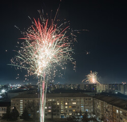 Naklejka premium Bright colorful and multi-colored fireworks on New Year's Eve over the city, fireworks explode over a residential city
