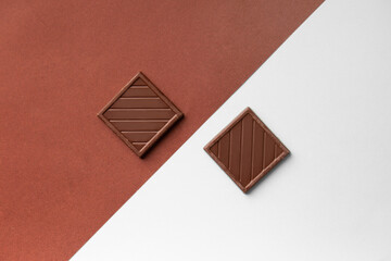 Milk chocolate bars on white and brown background top view.