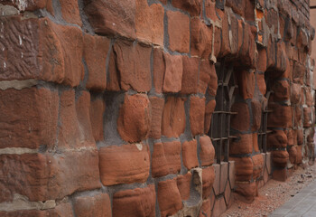Heavily eroded red façade of the building with windows. 