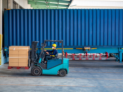 Forklift pjck up boxes on pallet from cotainer to storange in warehouse.