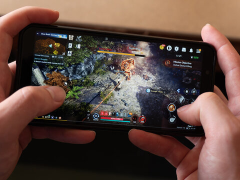 Cork, Ireland, July 31, 2022. A smartphone in the hands of a white man. Playing mobile MMORPG Black Desert Mobile. A Korean mobile game on a smartphone screen, illustrative editorial.