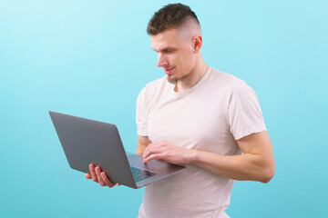 Smart young student smiling and using laptop on a blue background. Guy. Handsome. Model. Online....