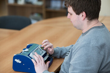 Blind man using braille typewriter. 
