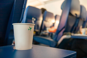 A cup with a beverage on a table in a flying plane. Refreshment with a drink on board the plane,...