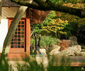 Woman doing yoga exercises in japanese garden in Hamburg next to Teahouse