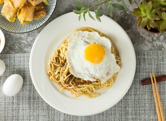 Black pepper sizzling noodles with sunny egg and chopsticks served in dish isolated on napkin top view on table taiwan food