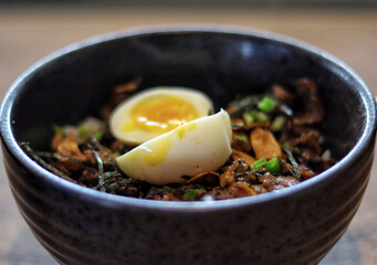 Truffle beef donburi Japanese rice topped with yakiniku beef, garlic chips, egg and truffle oil serve in the table.