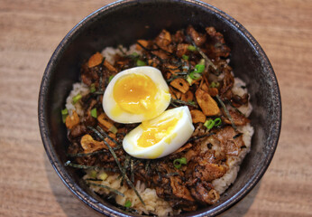 Truffle beef donburi Japanese rice topped with yakiniku beef, garlic chips, egg and truffle oil serve in the table.