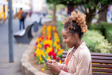 Girl sitting using a mobile phone in a park