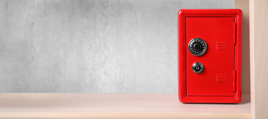 Red steel safe with mechanical combination lock on shelf, banner design. Space for text