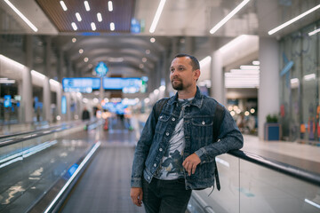 A man with a backpack moves to the gate on a travelator at the airport.