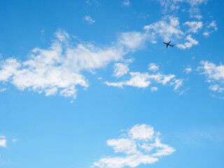 The passenger airplane is flying far away in the blue sky and white clouds. Aircraft in the air. International passenger air transportation. Background or backdrop