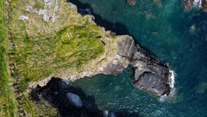 Grassy cliffs on the Atlantic Ocean coast. Landscape of Ireland from a height. Seaside rocks. Aerial photo. View from above.