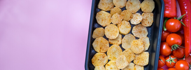 Raw potato slices with spices in a baking dish and vegetables. Banner