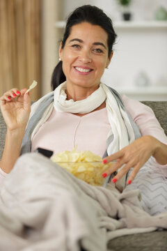 woman with bowl of potato chips sitting on sofa