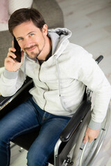 smiling young man in wheelchair talking on smartphone in office