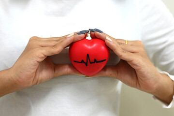 Young asian woman holding red heart pulse on her chest and heart position isolated on white...
