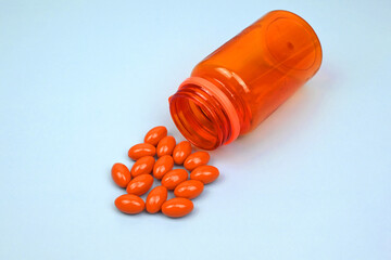 Orange supplements medical pills capsules and tablets spilling out of a drug bottle. Alternative...