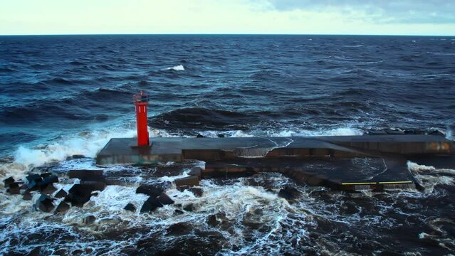 4K aerial view of a storm waves breaking on a lighthouse. The drone is circling around the lighthouse, birds are visible. Slow motion video of storm waves in the Gulf of Riga, Eastern Europe, Latvia.