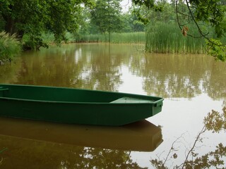 Obraz premium A tin fishing boat moored at the shore of a small pond