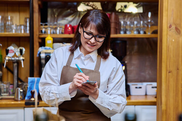 Woman working in restaurant writing in notebook