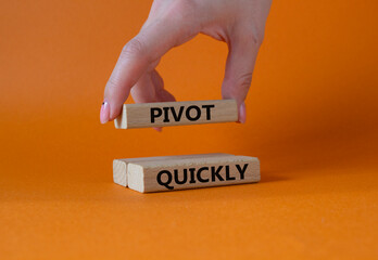 Pivot quickly symbol. Wooden blocks with words Pivot quickly. Businessman hand. Beautiful orange background. Business and Pivot quickly concept. Copy space.