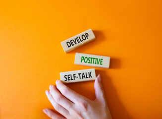 Develop positive self-talk symbol. Concept words Develop positive self-talk on wooden blocks. Businessman hand. Beautiful orange background. Business and Develop positive self-talk concept. Copy space © Natallia