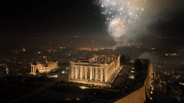 Aerial drone closeup night video of illuminated Acropolis hill and the Parthenon during New Year's eve 2022 with beautiful fireworks exploding, Athens historic centre, Attica, Greece
