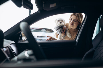 Woman with her dog by the car in a car showroom