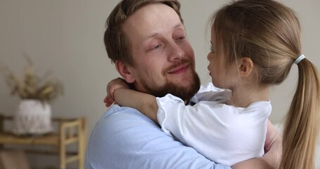 Loving dad cuddles his little 5s beautiful daughter, close up. Cheerful preschooler smiling girl enjoys warm communication and hugs of caring daddy. Happy Father Day, fatherhood and unconditional love