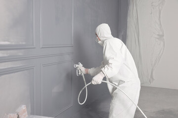 Decorator dyeing wall in grey color with spray paint indoors - obrazy, fototapety, plakaty