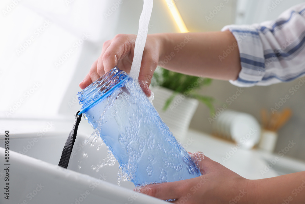 Wall mural Woman washing thermo bottle in kitchen, closeup