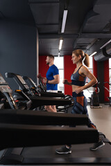 Fototapeta na wymiar Beautiful couple training on treadmills in gym