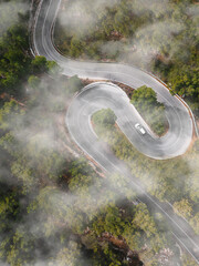 Aerial view of car driving down windy foggy road
