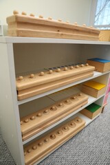 Obraz na płótnie Canvas Shelving unit with different wooden geometric puzzles in room. Montessori toy