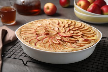 Tasty apple pie in baking dish on grey table