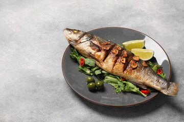 Plate with delicious sea bass fish and ingredients on light grey table, space for text
