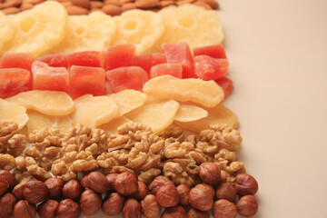 Different tasty nuts and dried fruits on beige background