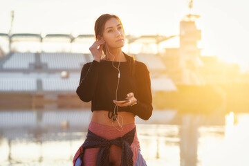 Portrait of a beautiful young female athlete with headphones in urban environment. Healthy lifestyle