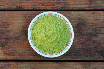 Delicious guacamole made of avocados on wooden table, top view
