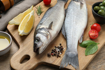 Sea bass fish and ingredients on wooden table, closeup