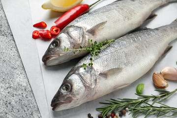 Sea bass fish and ingredients on grey table, closeup